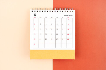 Directly above view of June 2024 desk calendar on orange background.