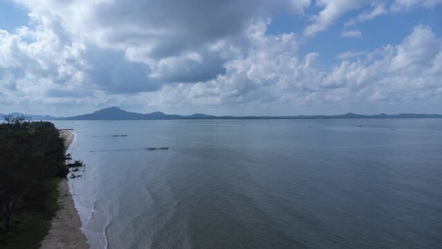 Time lapse view of the coastline with clouds and mountains in the background accompanied by sailing boats