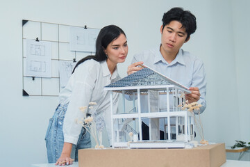 Portrait of cooperative engineer team working together to measure house model by using ruler and...