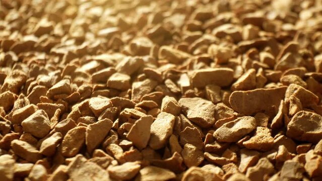 Dive into a mesmerizing close-up of freeze-dried coffee granules, revealing their rugged, uneven texture. The rich, golden-brown hue hints at an intense flavor preserved within.
