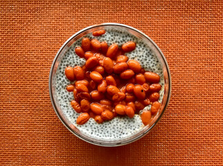 A lot of healthy Chia pudding with coconut milk in a glass containers can with fresh berries as sea-buckthorn on light red background. Close-up