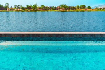 Natural landscape of swimming pool near river for tourism travel. Swimming pool with water views and views of the lake. Swimming pool that is not very clean near river. Summer travel vacation concept.
