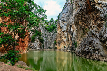 Beautiful nature scenic landscape with mountain range and beautiful hidden spot in Khao Ngu Stone Park at Ratchaburi, Thailand. Landscape view of mountain cliffs In green canyon lake. Amazing nature.