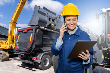 Female engineer with a digital tablet on the background of construction machines..