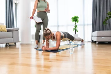 Fotobehang Persoonlijk Home workout with personal trainer. Two young women physiotherapist and client training for stability, body and mental health. Businesswoman paying professional coach to help her.  © Srdjan