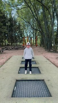 A teenage boy actively jumps over several trampolines in a row.
