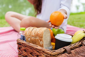 Picnic basket Wheat bakery fruit food and drinks in green park outdoor lifestyle. food bread fresh fruit coffee cup orange juice in wood wicker box on red Blanket. Breakfast healthy appetizer box