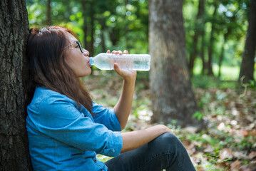 Young Woman Drinking Water bottle outdoor park traveler. Asian female drinking water bottle healthy...
