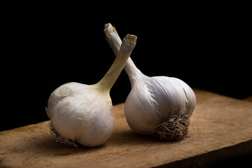 garlic on wooden board on black background