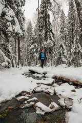 A tourist girl walks through a snow-covered forest with a backpack