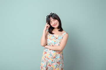 Asian woman with thinking pose against a pastel green background.