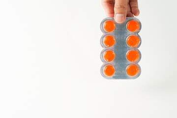 male hand holding blister of lozenges with cough drops on white background