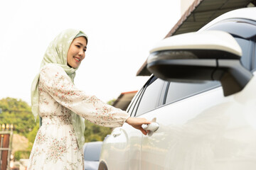 Muslim women opening a door into an EV car electric vehicle, traveling to places using automobile...