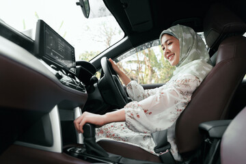 Asian muslim islamic woman driving in a car traveling using automobile for transportation to get to...