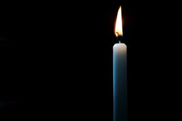 White Candle Burning in the Dark, Isolated on Black Background, Symbolizing Memorial Day Remembrance.