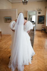 The bride in a beautiful white wedding dress goes elegantly