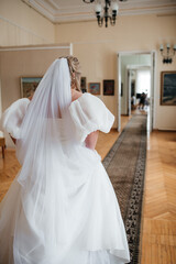 The bride in a beautiful white wedding dress goes elegantly