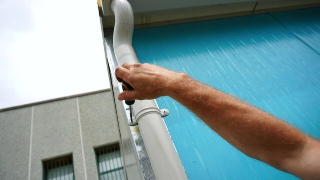 A worker fixes a drainpipe. How to install gutters with your own hands, in what order the elements of the drainage system are attached and installed