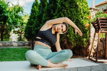 One young caucasian woman is doing yoga and stretching in backyard