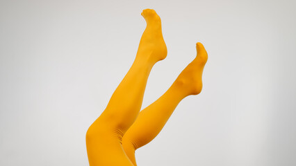 Female legs in ocher tights on a white background. Copy space. 