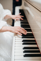 Fototapeta premium A girl in a white dress plays the piano
