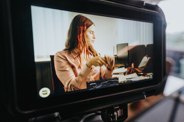 A professional young woman is deeply focused while working at her cluttered office desk, a scene...