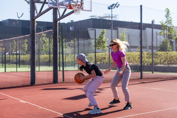 A Happy mother and child daughter outside at basketball court.
