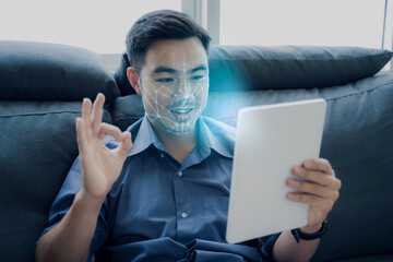 Asian businessman using computer tablet scanning  face ID to unlock device security with facial recognition technology for identification, with graphical technology illustration.
