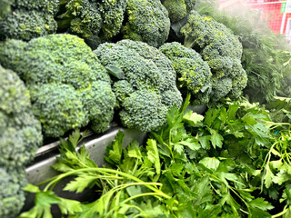 greens on the counter in a grocery store, vegetables for sale, broccoli, parsley and dill, healthy food