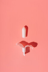 Unpacked white rectal candle on a pink background.