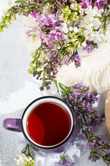 a cup of tea and a branch of lilac on a white background in a basket. Spring Postcard