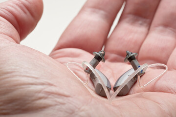 Close-up of a small discreet hearing aid in a male hand