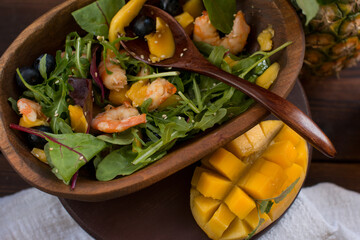 Fruit salad with shrimp, mango and green arugula leaves. Spicy diet salad sprinkled with sesame...