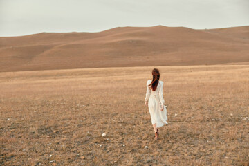 Fototapeta na wymiar Desert wanderer a woman in a white dress exploring the remote beauty of the open field