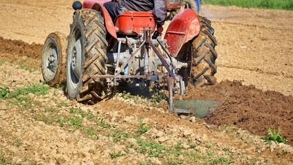 farmer on Red Tractor Plowing field on may , preparing for planting vegetables