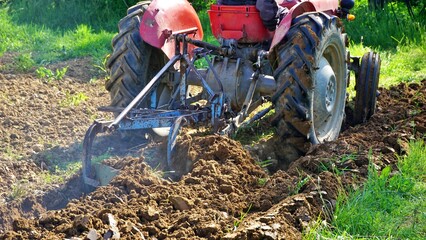 farmer on Red Tractor Plowing field on may , preparing for planting vegetables
