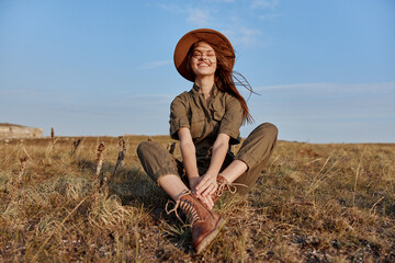 Woman in a hat enjoying nature on grassy field with blue sky in background, travel and beauty...