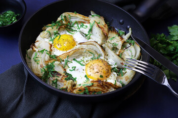Uova fritte fatte in casa e finocchio con erbe in padella su sfondo scuro. Cibo sano e vegetariano.