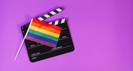 Clapper board and rainbow pride flag on purple background