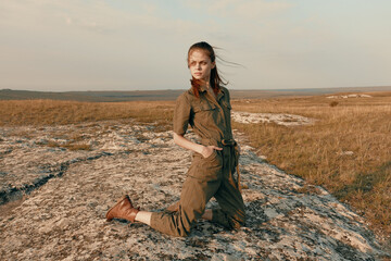 Woman sitting crosslegged on rock in field, contemplating nature and reflecting on life in solitude