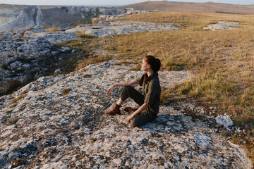 Solitude and serenity woman contemplating the horizon on cliff edge at sunset in travel and adventure concept
