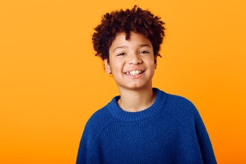 Bright and cheerful a joyful young african american boy in a blue sweater against a vibrant orange...