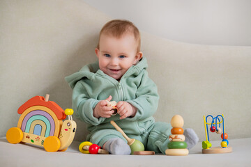 A baby is sitting on a couch with a variety of toys around him.