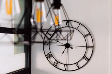 A black and white clock with Roman numerals on a wall