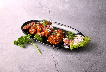 Barbeque honey glazed Chicken Wings with vegetable salad in a black bowl