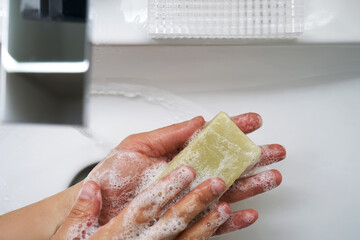 The process of washing hands with natural soap over the sink.