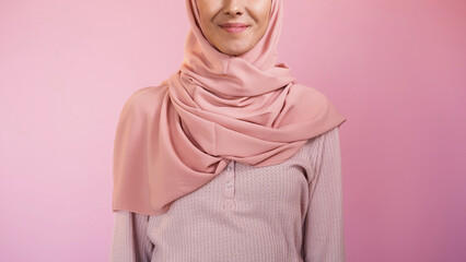 Muslim woman. Religious clothing. Unrecognizable smiling female face in islamic hijab modern headscarf isolated on pink copy space background.