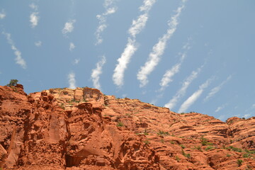 The red rocks of Sedona, Arizona, stand out beneath the white lines of clouds set against a blue...