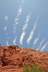 Close up of the red rocks of Sedona, Arizona, stand out beneath the white lines of clouds set...