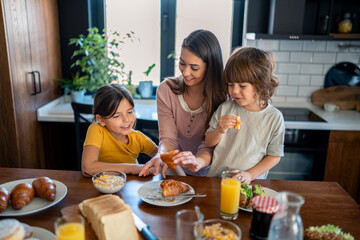 Kids having breakfast with mother.